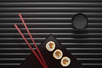 Chopsticks and sushi on square plate with dipping sauce