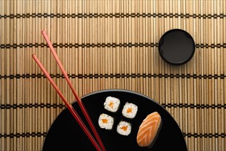 Chopsticks and sushi on round plate with dipping sauce