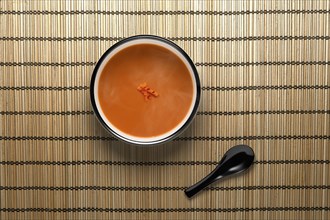 Orange soup in bowl with black spoon