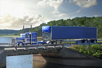 Semi-truck driving on bridge over river