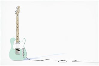 Green guitar balancing on white background