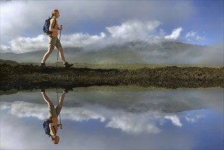 Reflection of Caucasian girl hiking at river