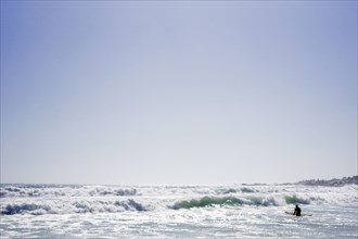 Surfer holding surfboard in ocean waves