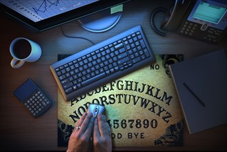 Hands using computer mouse on Ouija board