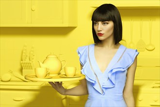 Caucasian woman in yellow old-fashioned kitchen holding tea service