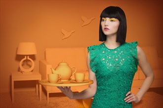 Caucasian woman in orange old-fashioned livingroom holding tea service