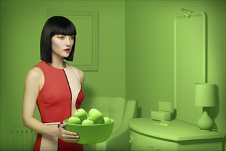 Caucasian woman in green old-fashioned bedroom carrying bowl of apples