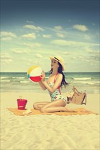 Caucasian woman holding beach ball on beach