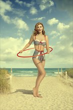 Caucasian woman wearing bikini holding plastic hoop at beach