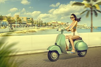 Caucasian woman riding scooter at beach
