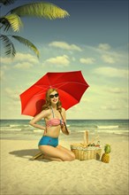 Caucasian woman holding red umbrella at beach