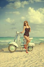 Caucasian woman posing on scooter at beach