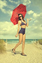Caucasian woman holding polka-dot umbrella at beach