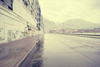 Wet street near warehouse with graffiti