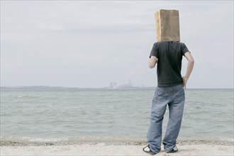 Man wearing paper bag on head watching distant skyline