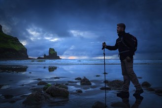 Caucasian hiker standing on beach at sunset