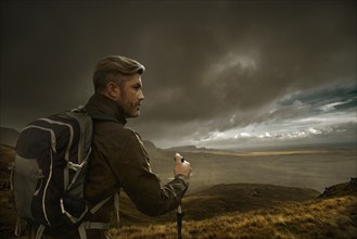 Caucasian hiker holding walking in cloudy landscape