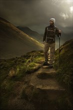 Caucasian hiker holding walking stick on mountain path