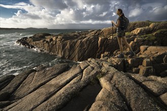 Caucasian woman hiking on rocks near ocean