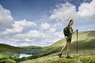 Caucasian woman hiking on green hill