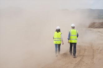 Construction workers walking in cloud of dust