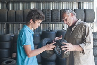 Hispanic grandfather and grandson looking at go-cart tires