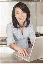 Korean woman using laptop in kitchen