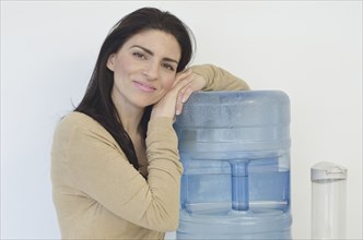 Hispanic businesswoman leaning on water cooler