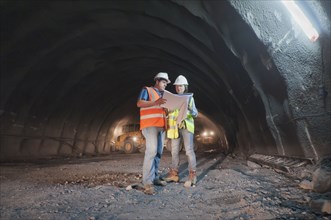 Construction workers looking at blueprint in tunnel
