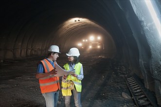 Construction workers looking at blueprint in tunnel