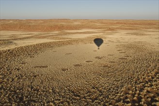 Shadow of hot air balloon over desert
