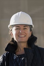 Mature female engineer wearing hard hat smiling portrait
