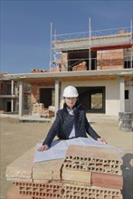 Female architect on construction site looking at plan portrait