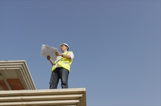 Engineer looking at plan on construction site low angle view