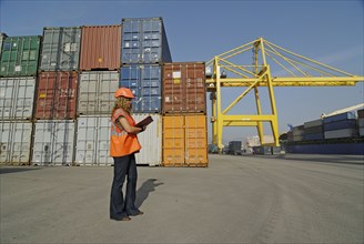 Female worker with clipboard in cargo container terminal