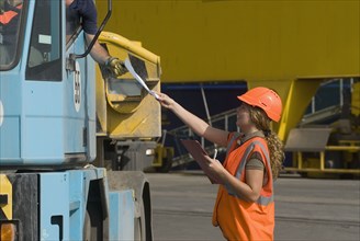 Woman wearing hard hat handing document to man in lorry smiling