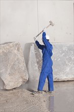 worker attacking marble block with sledgehammer
