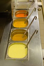 Colored sauces with ladles in restaurant kitchen