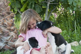 young girl geting kissed by dog in garden