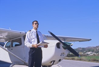 Pilot Holding a Map and Standing by a Private Propeller Plane
