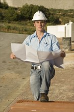 Young architect with plan on construction site