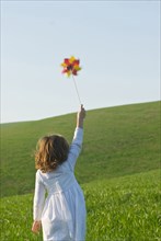 Girl holding up pinwheel in field