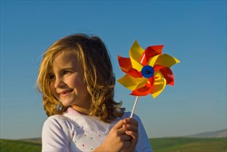 Girl holding pinwheel in field