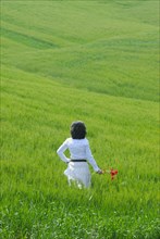Woman standing in field rear view