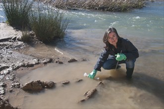 female scientist taking water sample in stream