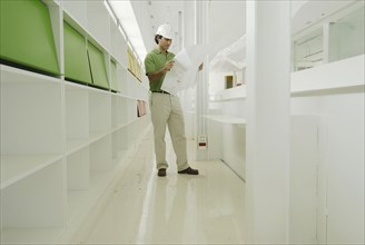 Male architect looking at plan in recently finished office building