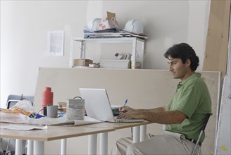 Male architect using laptop on makeshift desk in site office