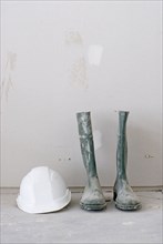 Pair of dirty work boots and white hard hat