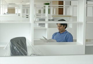 Male office worker looking at documents in newly finished office