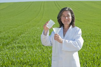 female scientist with test tube in green field